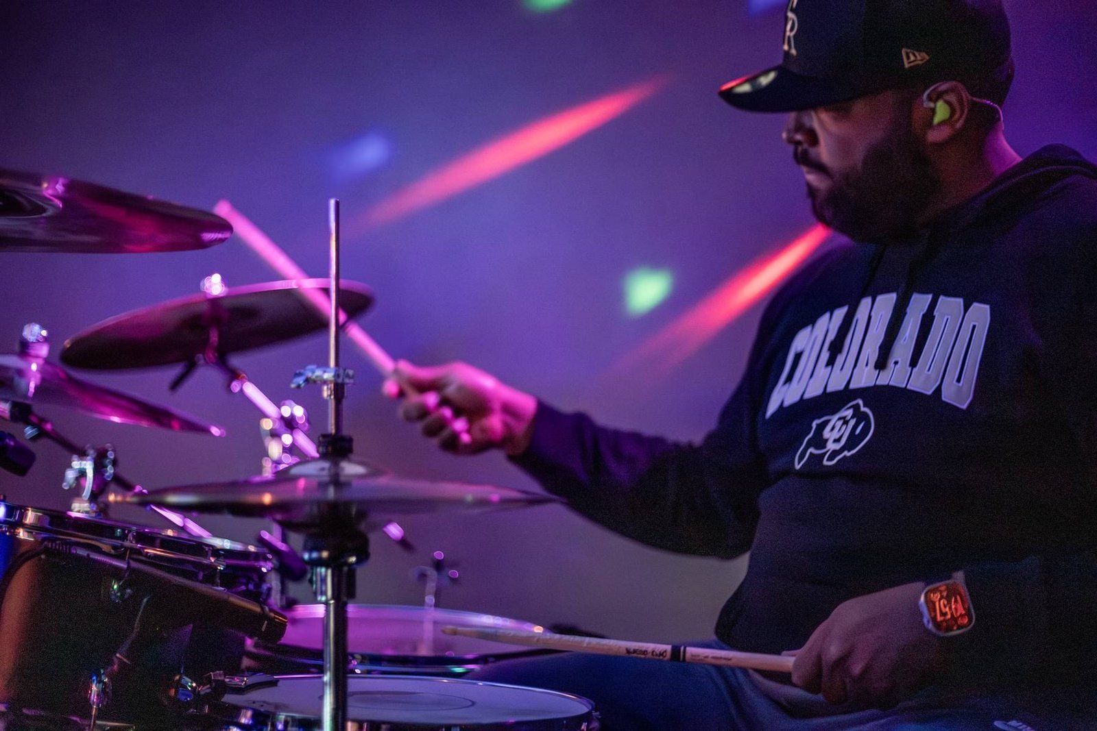 Drummer performing under pink and purple stage lights